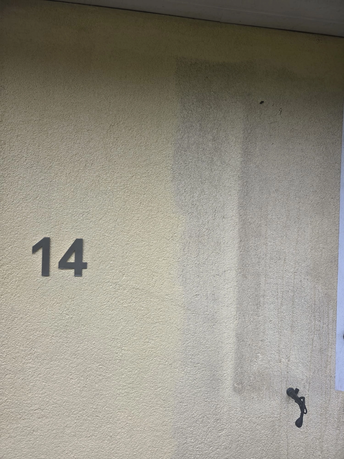 Duka Reinigung - Gebäudereinigung - Strukturierte Stuckwand mit einem sauberen beigen Bereich links und einem schmutzigen, dunkelgrauen Streifen rechts.