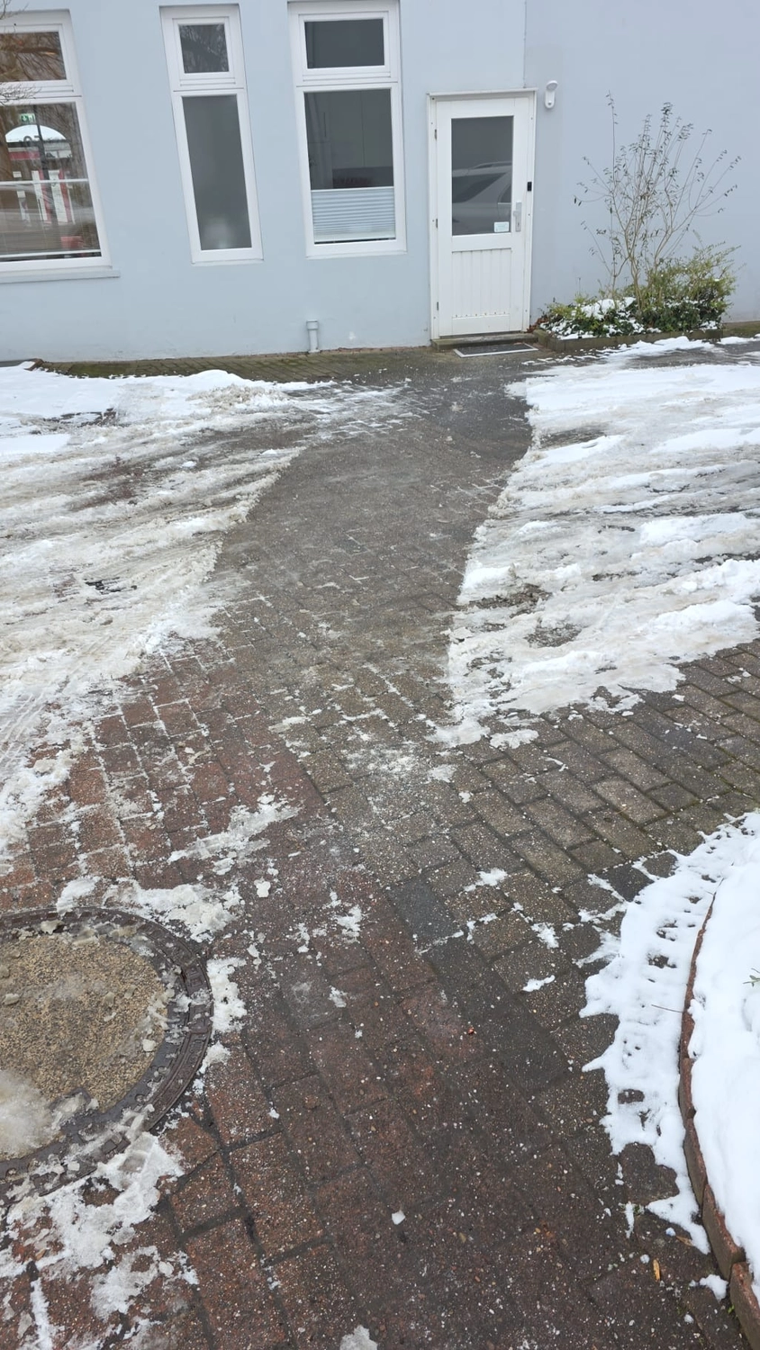 Duka Reinigung - Gebäudereinigung - Ein teilweise von Schnee und Schneematsch geräumter Backsteinweg